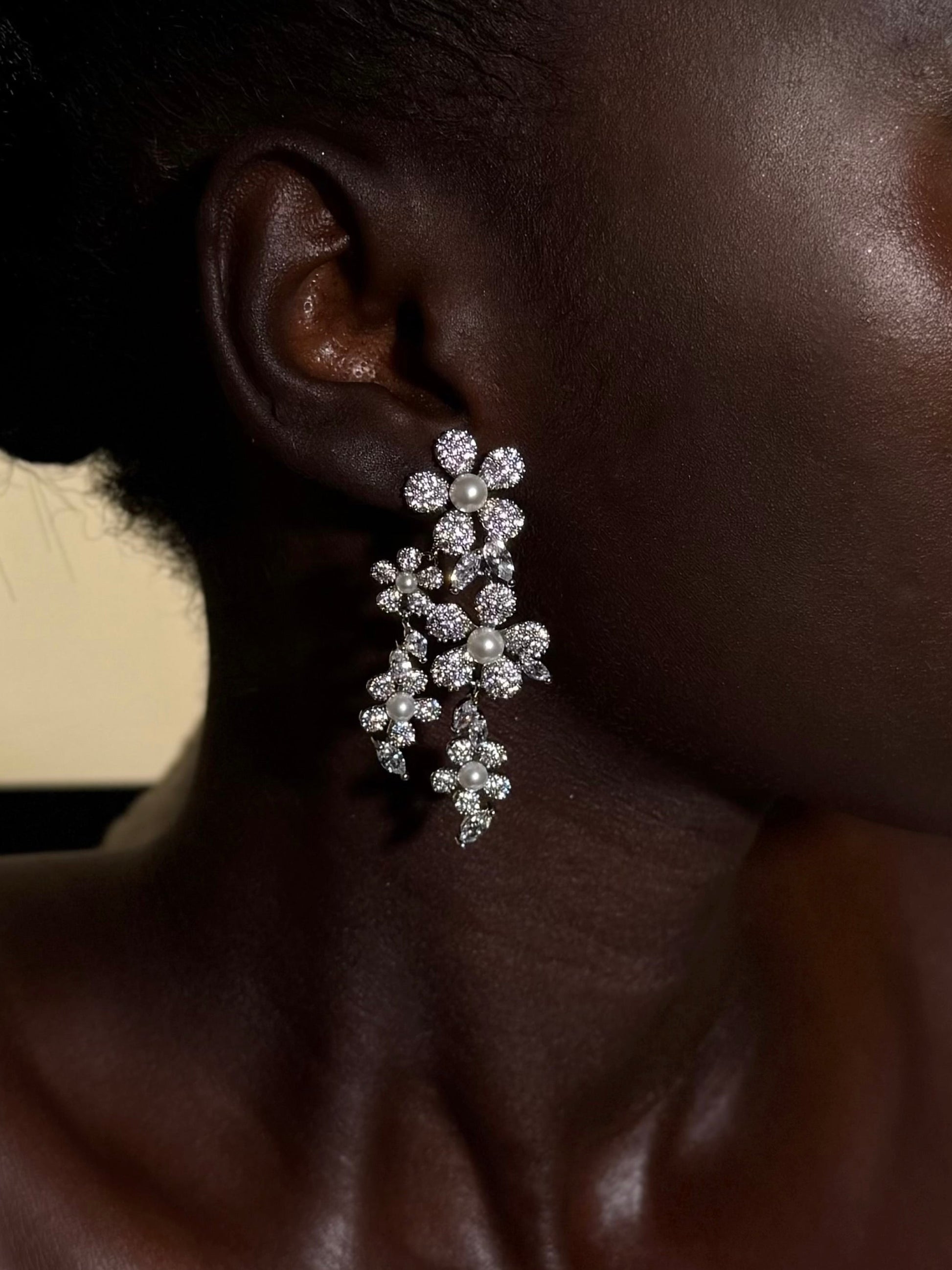 Close-up of a woman wearing a sparkling earring against a neutral background